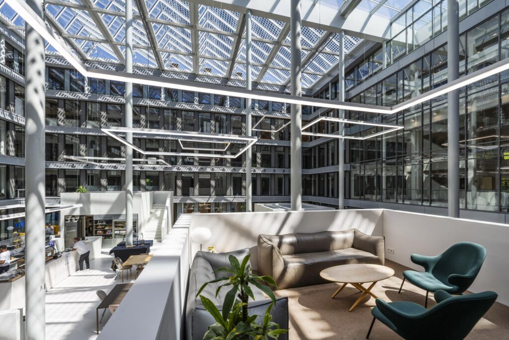 Modern atrium with glass roof at Mr. Treublaan featuring lounge seating, office space, and natural light.